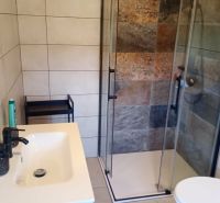 A bathroom in a holiday apartment with a modern shower and sink.