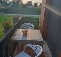 Balcony of a holiday apartment in Bibione with rattan seating and a view of greenery.