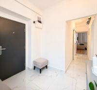 A hallway with white walls, tiles, and dark doors in a 3-room apartment.