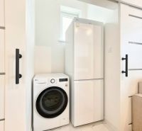 Laundry room in a 3-room apartment, washing machine and refrigerator, white sliding doors.
