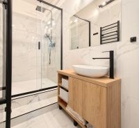 A bathroom in a 3-room apartment with a shower corner and a cabinet with a wooden decor.