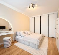 A bedroom in a 3-room apartment with white furniture and a wooden decor floor.
