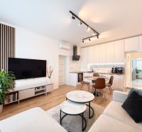 Living room with kitchen in a 3-room apartment, white cabinets, floor with wood decor.