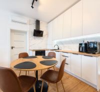 A kitchen in a 3-room apartment with white cabinets and a wood-patterned floor.