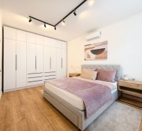 Bedroom with a built-in wardrobe, bed, and floor with a wood decor in a 3-room apartment.