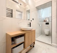 A bathroom with a modern sink and shower in a 3-room apartment, floor with wood decor.