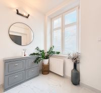 Duplex interior with a window, green plants, and a gray dresser in a 3-room apartment.