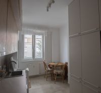 Kitchen of a one-room apartment with a dining area and modern cabinets.