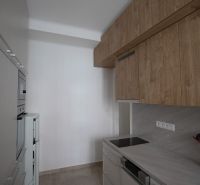 A kitchen in a studio apartment with wooden cabinets and modern appliances.
