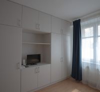 Built-in wardrobes with a television and a blue curtain in a studio apartment.