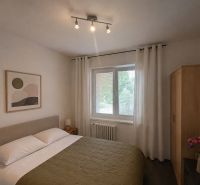 A bedroom in a 4-room apartment with a bed, a painting, and wooden furniture.