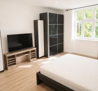 Bedroom in a 3-room apartment with light furniture and a television, floor with wooden decor.