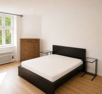 A bedroom in a 3-room apartment with a wooden decor floor, a bed, and a dresser.