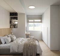A bedroom with wood-patterned flooring, a bed, and built-in cabinets in a 2-room apartment.