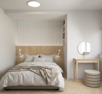 Bright bedroom in a 2-room apartment with a bed and a dressing table, wooden decor flooring.