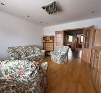 Living room in a 4-room apartment with floral furniture and a wooden decor floor.