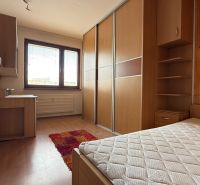 A room with a wardrobe, a wooden-decor floor, and a desk in a four-room apartment.