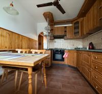 A kitchen in a 4-room apartment with wooden cabinets and a dining table with a ceramic top.