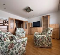 Living room in a 4-room apartment with a wooden decor floor and floral furniture.