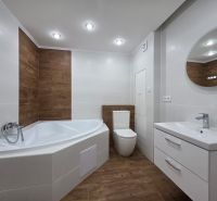 Bathroom in a 3-room apartment with a bathtub, sink, and floor with a wooden decor.