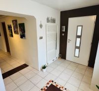 A hallway in a family house with tiles, decorations, and paintings on the walls.