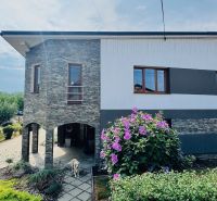 A family house in Radobica with a stone facade, a garden, and flowers in front of the building.