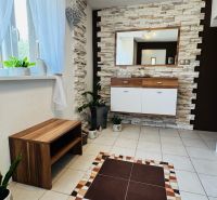 Interior of a family house with tiles, decorative stones on the wall, and wooden furniture.