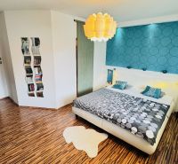 A bedroom in a family house with colorful wallpaper and a wooden decor floor.