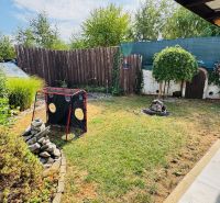 Garden of a family house in Radobica with a lawn, shrubs, and a wooden fence.