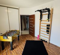 Home gym with a wall bar, foosball table, and floor with wood decor.