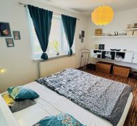 A bedroom in a family house with a wooden decor floor and colorful textile accessory.