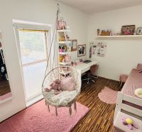 Children's room with a swing, bed, and desk, floor with wooden decor.