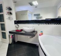 A bathroom in a family house with a modern sink, bathtub, and decorative accessories.