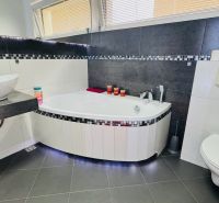 Bathroom in a family house with a wall-hung toilet, bathtub, and sink.
