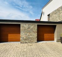 The family house in Radobica has a garage with wooden doors and a brick decor.