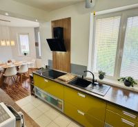 Interior of a family house with a kitchen, dining table, and wooden decor flooring.