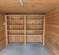 Garages with wooden decor, empty shelves, concrete floor.