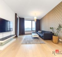 A stylish living room with a wood-patterned floor, a dark gray sofa, and a wall-mounted television.