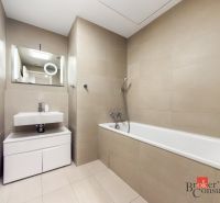 Bathroom with a bathtub and a sink, light tiles, ideal for a 2-room apartment.