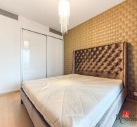 A bedroom in a two-room apartment with an upholstered bed and wallpapered walls.