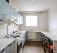 A kitchen with a gas stove and wooden chairs in a 4-room apartment.