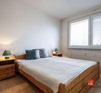 A bedroom with a bed, nightstands, and a wooden decor floor in a 4-room apartment.