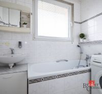 Bathroom with a mirror, bathtub, and washing machine in a 4-room apartment. White tiles with a pattern.