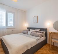 Bedroom in a 3-room apartment, with a bed, mirror, and wooden decor flooring.