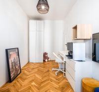 A study with a wooden decor floor in a 3-room apartment, white cabinets, and a TV.