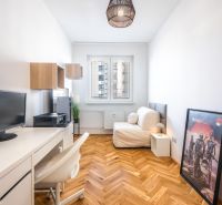 A workspace in a 3-room apartment with a wooden decor floor, a white table, and a sofa.