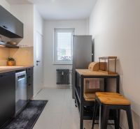 A kitchen with black cabinets, wooden details, and modern appliances in a three-room apartment.