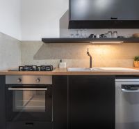 A kitchen in a 3-room apartment with a stove, dishwasher, and wooden decor on the countertop.