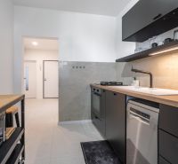 A kitchen with light walls, dark furniture, and appliances in a 3-room apartment.