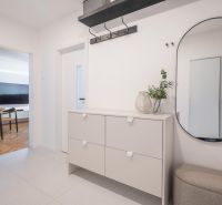 Entrance hall in a 3-room apartment with furniture, a mirror, and a view into the living room.